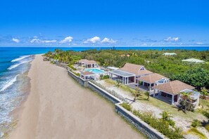 A beachfront property with multiple villas, a swimming pool, and a beach view. - Turtle Nest vibrant tropical garden (Les Terres Basses)
