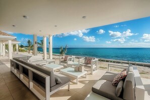 A modern outdoor seating area with a view of the ocean. - Turtle Nest vibrant tropical garden (Les Terres Basses)