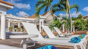 Ein Poolbereich mit weißen Liegestühlen und einer Holzterrasse.