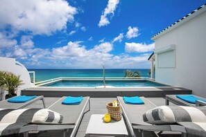 A poolside area with lounge chairs and a view of the ocean. - Sea Esta   Shore Pointe Community Villa (Saint Martin)