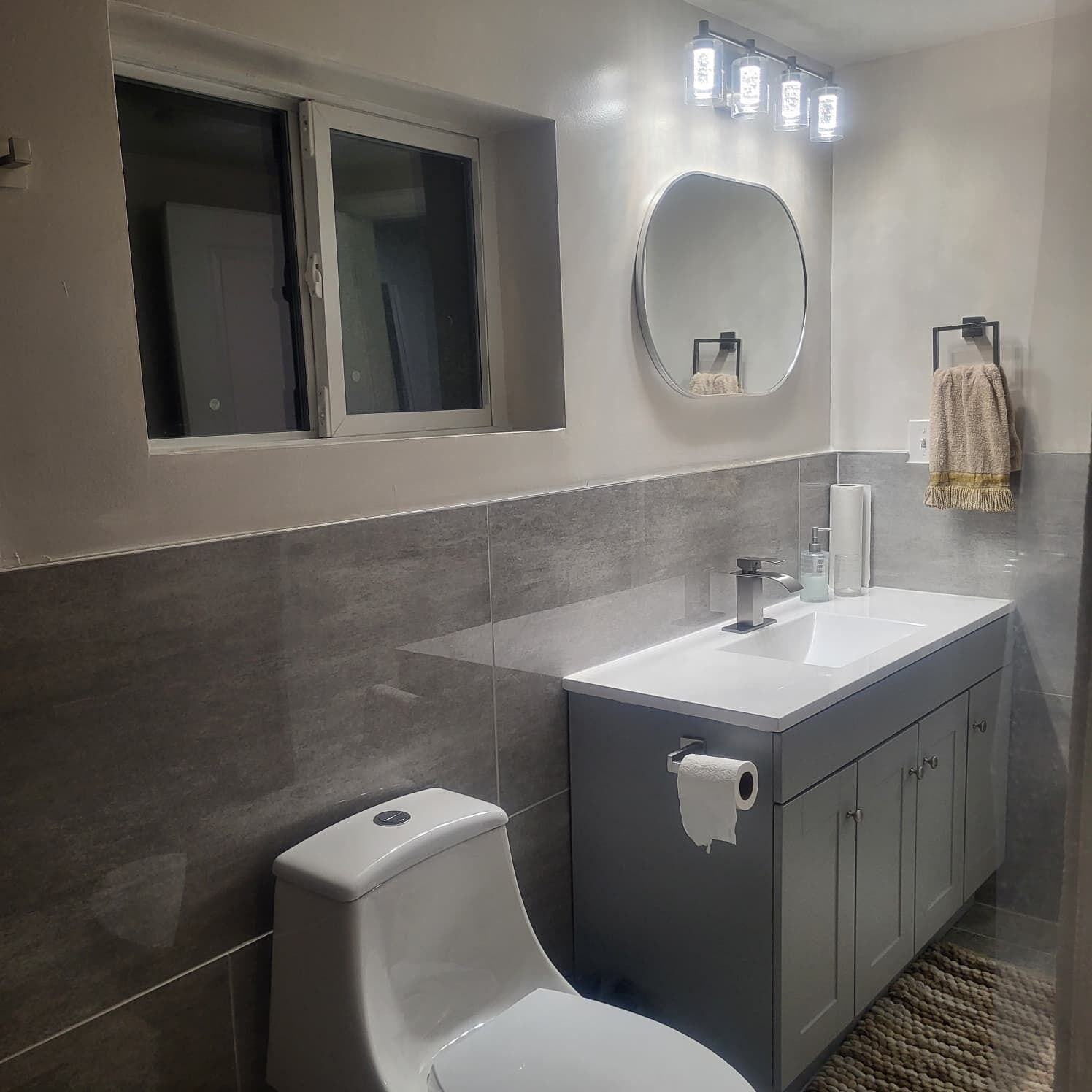 Un baño moderno con inodoro, lavamanos y espejo.