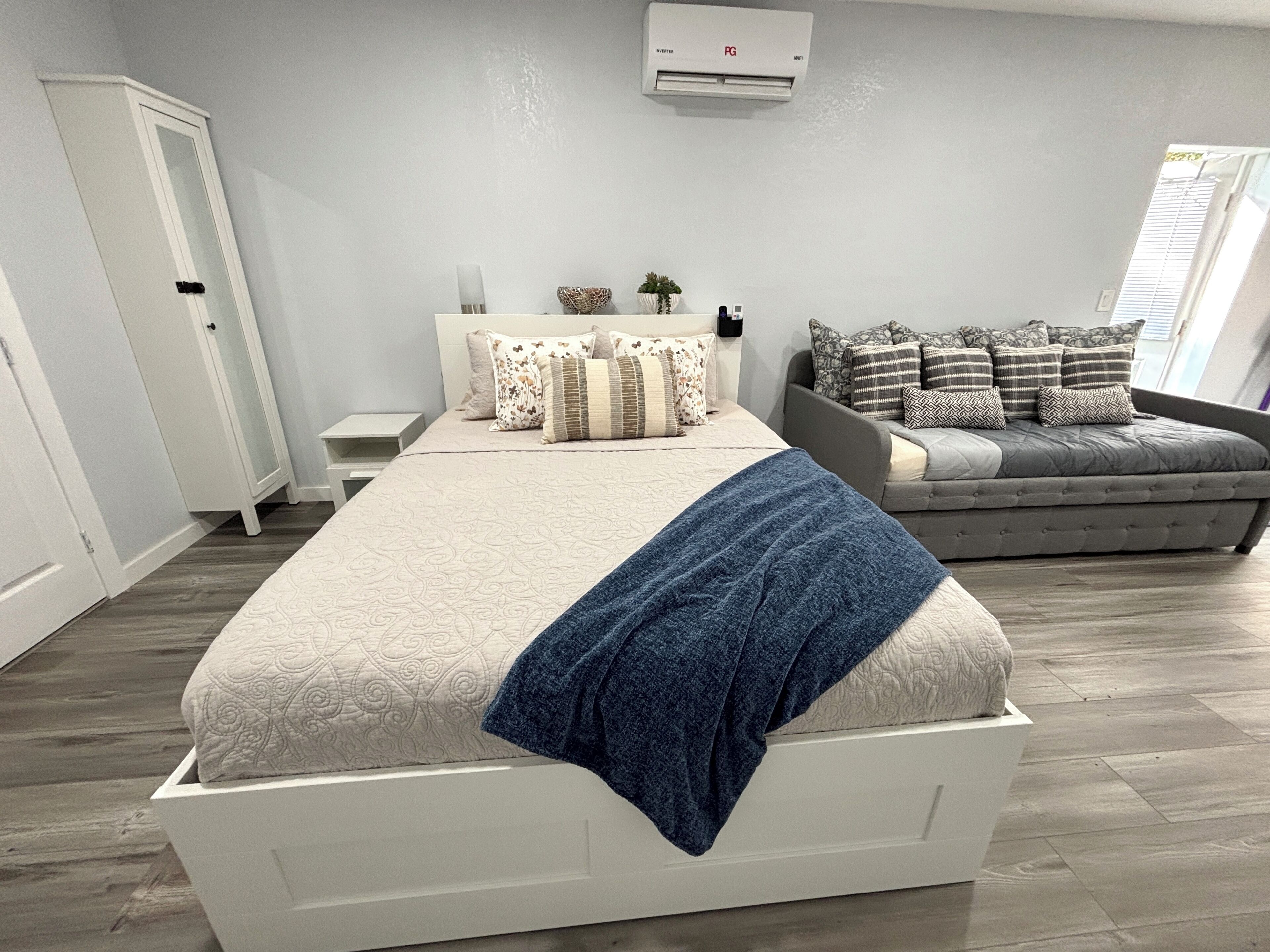 Een slaapkamer met een bed, een bank en een airconditioning.
