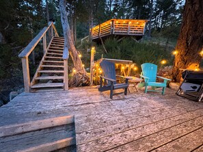 A wooden deck with a staircase leading up to a platform, surrounded by trees. - Oceanfront property in Pender Harbour with a dock, wrap around balcony with view (Garden Bay)
