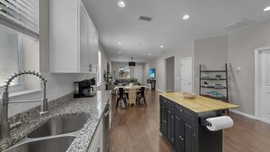 A modern kitchen with granite countertops, stainless steel appliances, and a central island with a wooden top. - Cozy Downtown Tampa Retreat (Tampa)