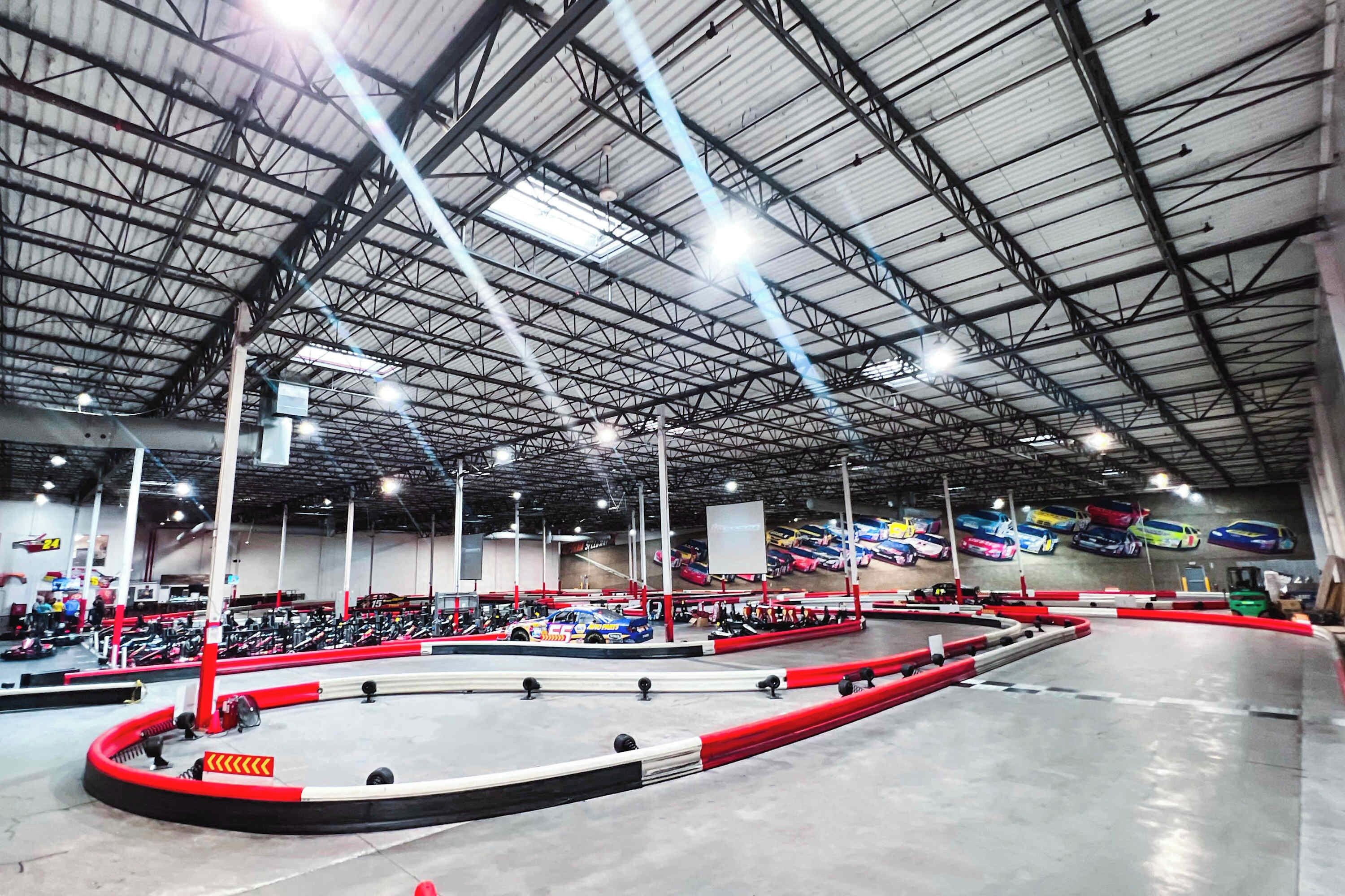 An indoor go-kart racing track with multiple lanes and a high ceiling.