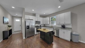 A modern kitchen with white cabinets, stainless steel appliances, and a wooden island. - Cozy Downtown Tampa Retreat (Tampa)