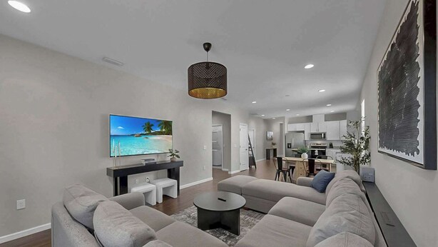 A modern living room with a large sectional sofa, a flat-screen TV, and a dining area with a kitchen in the background. - Cozy Downtown Tampa Retreat (Tampa)