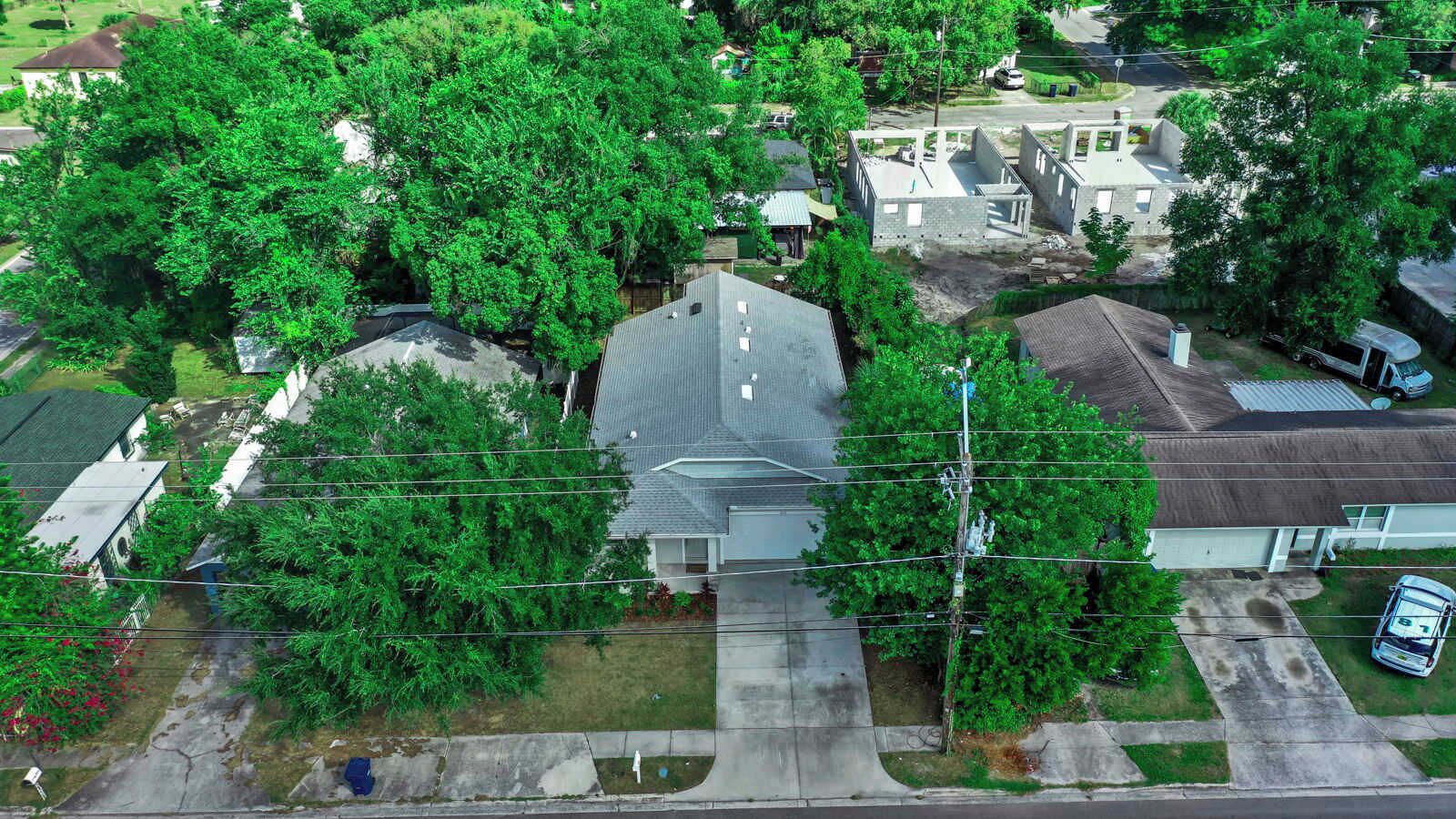 An aerial view of a residential area with houses, trees, and a clear road.
