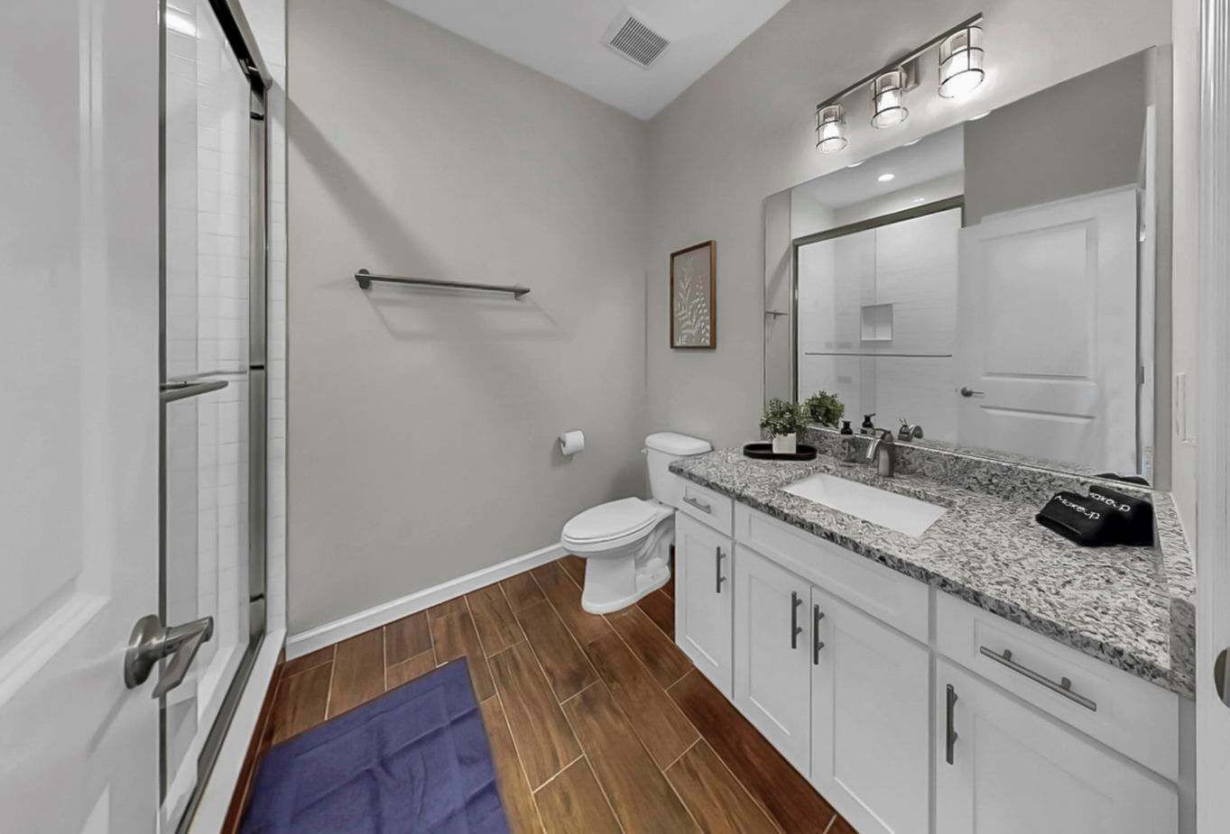 A modern bathroom with a shower, toilet, and vanity with a mirror and sink.
