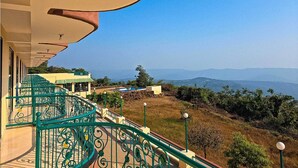 A balcony with a view of a pool and mountains. - Wilson Valley Resort (Dharampur)