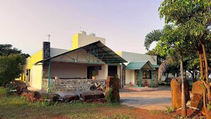 A two-story building with a covered patio area, stone walls, and a motorcycle parked outside. - Wilson Valley Resort (Dharampur)