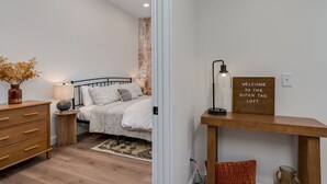 Une chambre à coucher avec un lit, une table de chevet, une lampe et un panneau d’accueil.