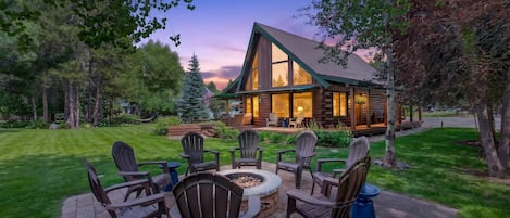 A log cabin with a patio area featuring outdoor furniture and a fire pit.