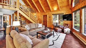 A wooden interior with a staircase, living room with sofas, a coffee table, and a TV. - McCall A-Frame on Golf Course, 5 Minutes from Town + Huge Yard, Hot Tub & 7 Beds (McCall)