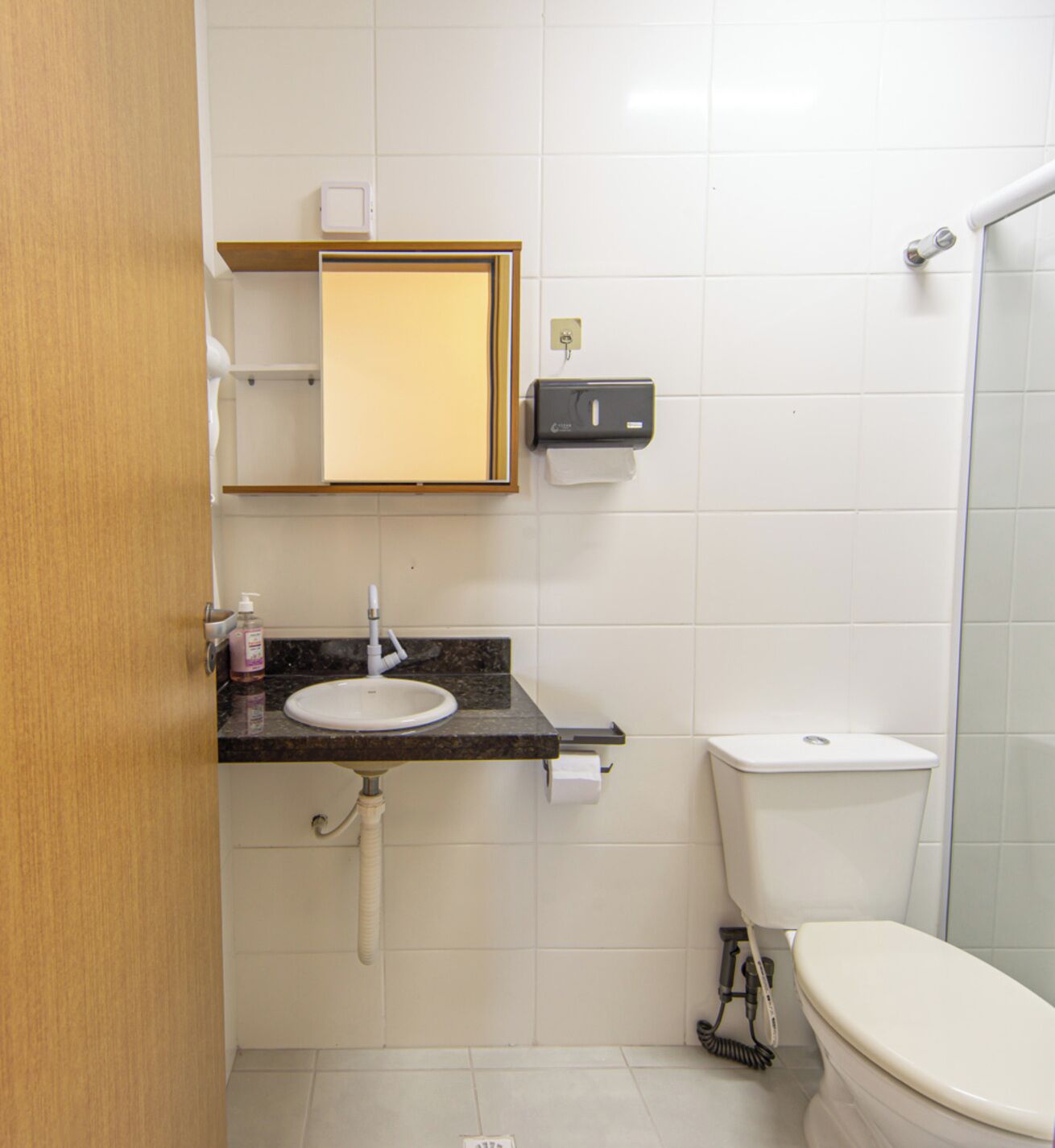 A bathroom with a sink, toilet, and a hand dryer.