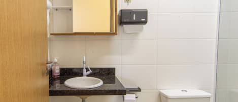 A bathroom with a sink, toilet, and a hand dryer.