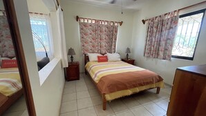 A bedroom with a bed, two bedside tables, a ceiling fan, and curtains. - MARAVILLA: Spacious 1-bedroom apartment with AC in charming Celestún. (Celestún)