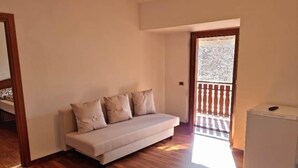 A room with a sofa, a small white appliance, and a wooden floor. - Apartment 1 "Vallonina" (Leonessa)