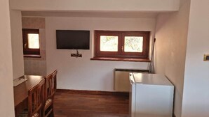 A compact kitchen with a refrigerator, a dining table with chairs, and a TV mounted on the wall. - Apartment 1 "Vallonina" (Leonessa)