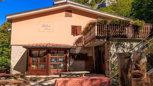 A hotel with a stone facade, wooden balcony with flowers, and outdoor seating. - Apartment 1 "Vallonina" (Leonessa)