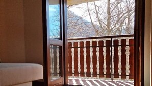A room with a wooden floor, a beige sofa, and a sliding glass door leading to a balcony with a wooden railing. - Apartment 1 "Vallonina" (Leonessa)