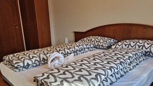 A double bed with patterned bedding, a wooden headboard, and a wooden wardrobe in the background. - Apartment 1 "Vallonina" (Leonessa)