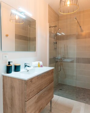 A modern bathroom with a wooden vanity, a large mirror, and a glass shower enclosure. - Duo Villas – 6BR, 2 Pools, Beach 500 m (Sérignan)