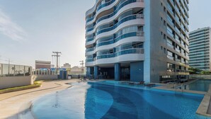 A modern hotel with a pool area, featuring a multi-story building with balconies and a clear sky. - Your Exclusive Stay in a Building With a Pool Just Steps From the sea - WJA (Salvador)