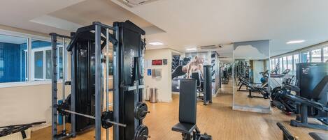 Un gimnasio con diverso equipo de ejercicio, que incluye una estructura para sentadillas y bancos de pesas.