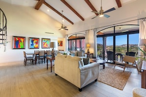 A spacious living room with a high ceiling, wooden beams, a dining area, and a balcony with a view. - Luxury Condo at Reserva Conchal with Incredible Ocean Views and Exclusive Beach Club Access (Brasilito)