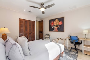 A bedroom with a bed, a desk, a chair, a ceiling fan, and a painting on the wall. - Luxury Condo at Reserva Conchal with Incredible Ocean Views and Exclusive Beach Club Access (Brasilito)