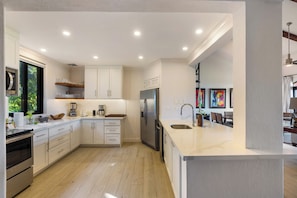 A modern kitchen with white cabinetry, stainless steel appliances, and a large island with a sink. - Luxury Condo at Reserva Conchal with Incredible Ocean Views and Exclusive Beach Club Access (Brasilito)