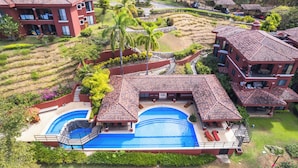 A resort with multiple buildings, a central swimming pool, and landscaped gardens.