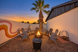 An outdoor seating area with chairs and a fire pit, surrounded by a wall with a mural, under a clear sky. - The Pine Desert Retreat - Scottsdale's Ultimate Getaway (Scottsdale)