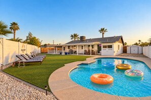 Un jardin avec une piscine, des chaises longues et un patio couvert.