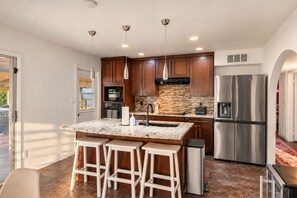 A modern kitchen with a central island, stainless steel appliances, and pendant lighting. - The Pine Desert Retreat - Scottsdale's Ultimate Getaway (Scottsdale)