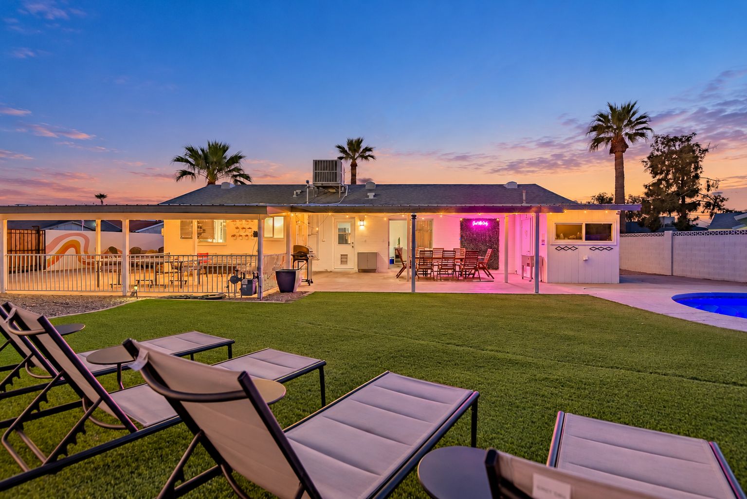 Ein modernes Haus mit einer überdachten Terrasse, Sitzgelegenheiten im Freien und einem Swimmingpool.