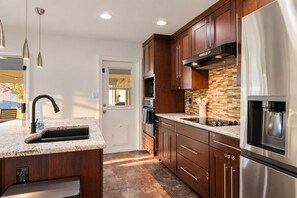 A modern kitchen with a stainless steel refrigerator, a built-in oven, and a granite countertop. - The Pine Desert Retreat - Scottsdale's Ultimate Getaway (Scottsdale)