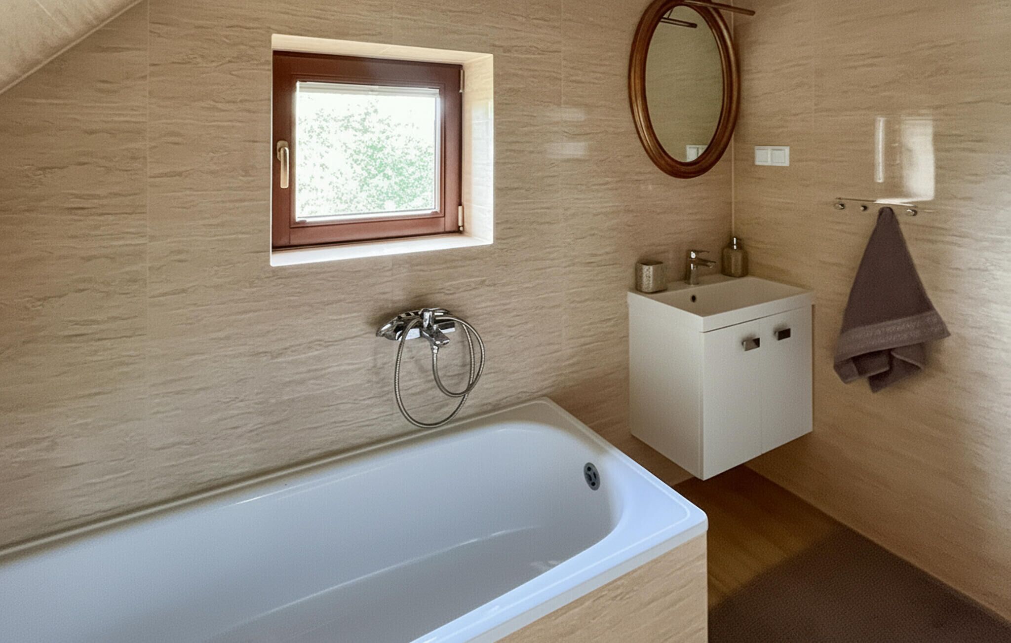 Een badkamer met een bad, een raam, een wastafel en een spiegel.