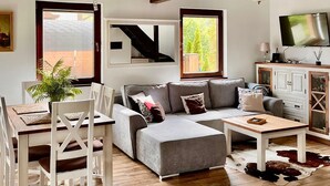 A modern living room with a grey sectional sofa, white chairs, a wooden coffee table, and a cowhide rug. - Amazing home in Prokowo with sauna (Prokowo)