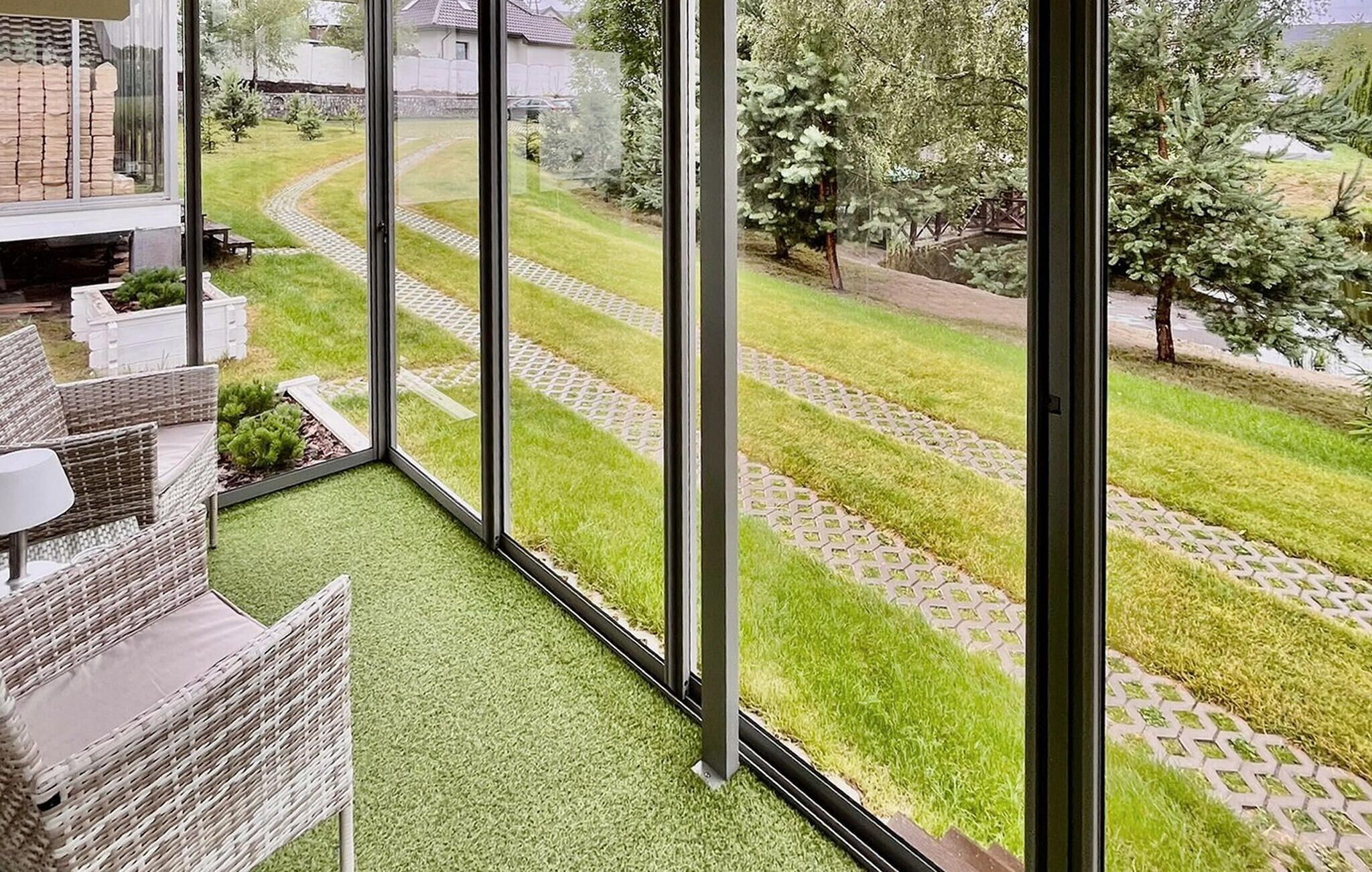 A balcony with a view of a well-maintained garden, a paved pathway, and a brick wall.