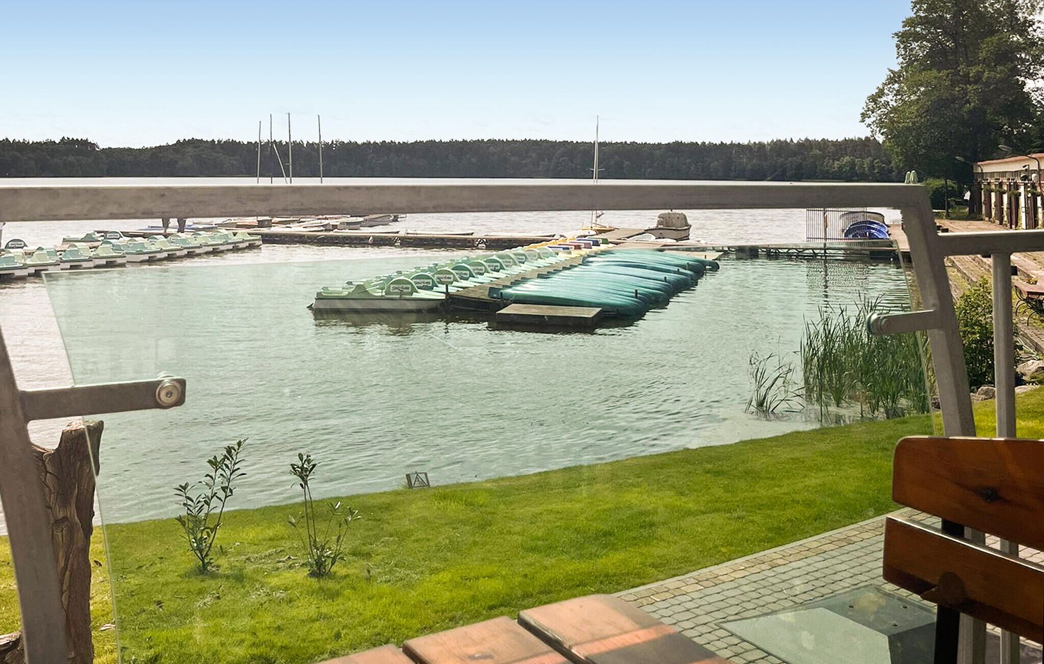 En småbåtshamn med förtöjda båtar, en gräsyta i förgrunden och en utsikt över vattnet.