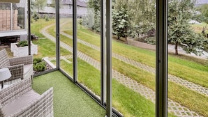 En balkon med udsigt over en velholdt have, en belagt sti og en murstensmur.
