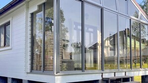 Et hus med store glasvinduer og en stensokkel.