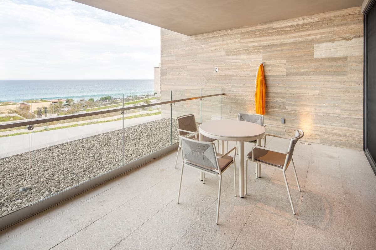 Un balcon avec vue sur la mer, une table ronde avec des chaises et un mur moderne sur lequel est accrochée une serviette.