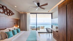 A modern hotel room with a large bed, a desk, and a view of the ocean. - Solaz Club (San José del Cabo)