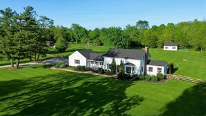A large white house with a dark roof, surrounded by a well-maintained lawn and trees. - Hot Tub • Fenced Yard • Perfect Family Retreat Near Chagrin Falls (Geauga County)