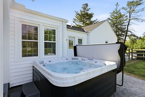 A hot tub outside a house with a wooden deck and a picnic table nearby. - Hot Tub • Fenced Yard • Perfect Family Retreat Near Chagrin Falls (Geauga County)