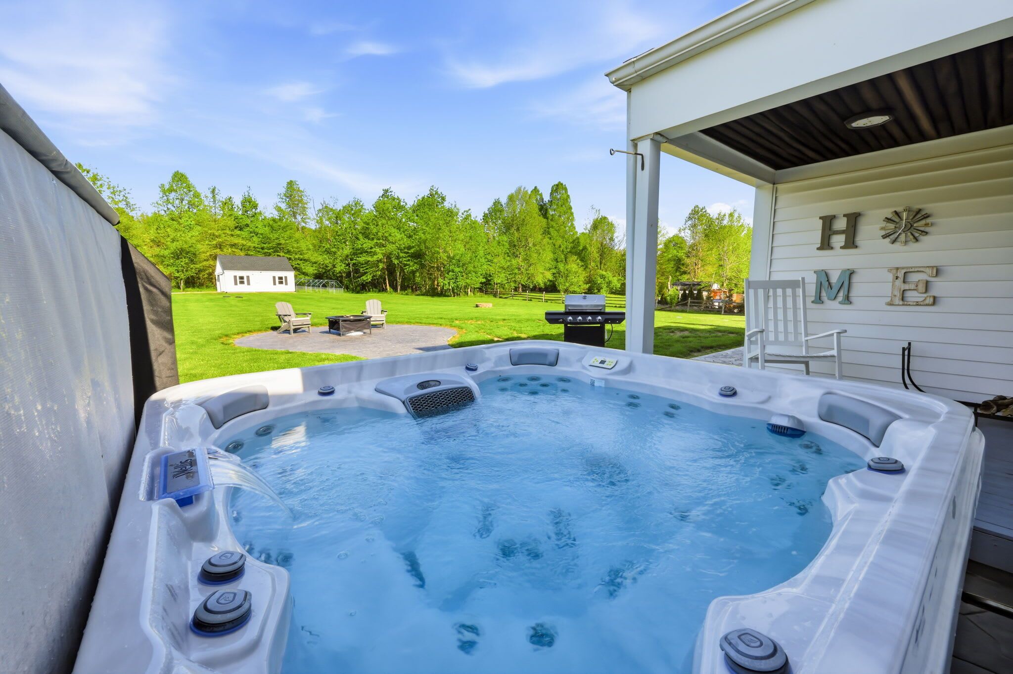 A hot tub with a view of a grassy yard and a house in the background.