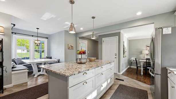 A modern kitchen with a large island, pendant lighting, and a view to the outside. - Hot Tub • Fenced Yard • Perfect Family Retreat Near Chagrin Falls (Geauga County)